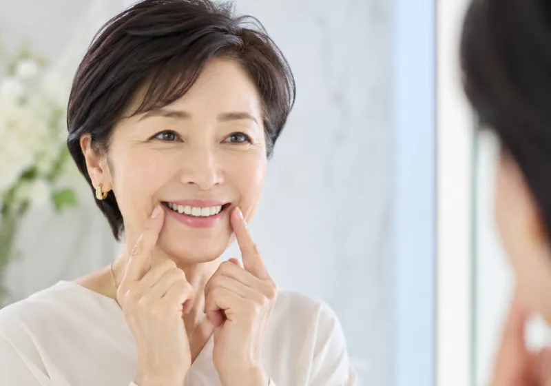 鏡を見ながら笑顔を確認する女性